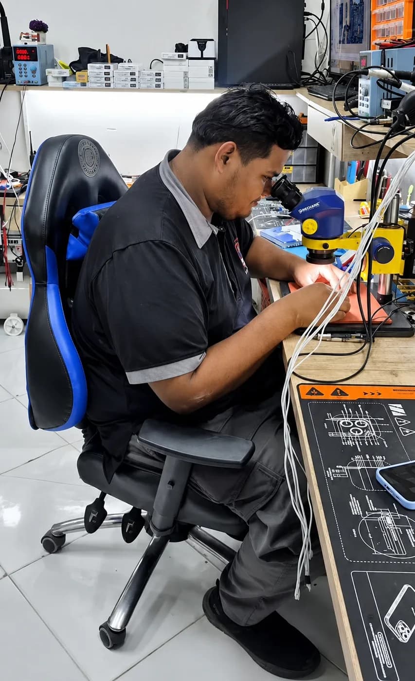 Técnico reparando un celular bajo el microscopio en el laboratorio de BandaMóvil