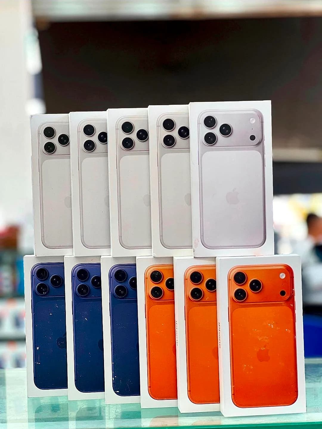 Cajas de iPhone blancos, azules y naranjas apiladas en la vitrina de la tienda